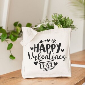 May include: White canvas tote bag with black text that reads "Happy Valentines Day" with hearts and an arrow.