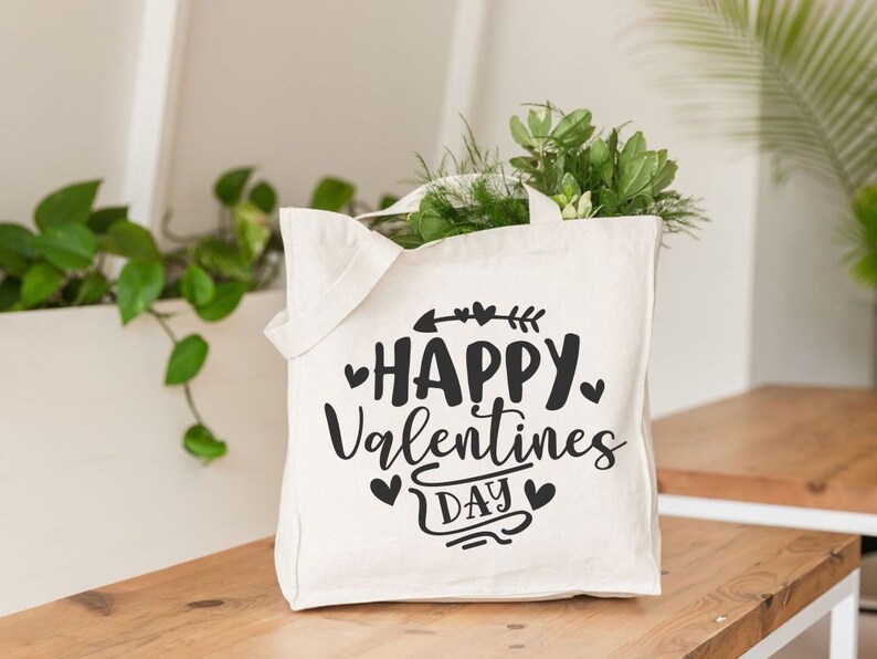 May include: White canvas tote bag with black text that reads "Happy Valentines Day" with hearts and an arrow.