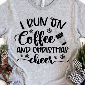 May include: Gray long-sleeve shirt with black text that reads "I run on coffee and christmas cheer" with a snowflake and a cup of coffee graphic.
