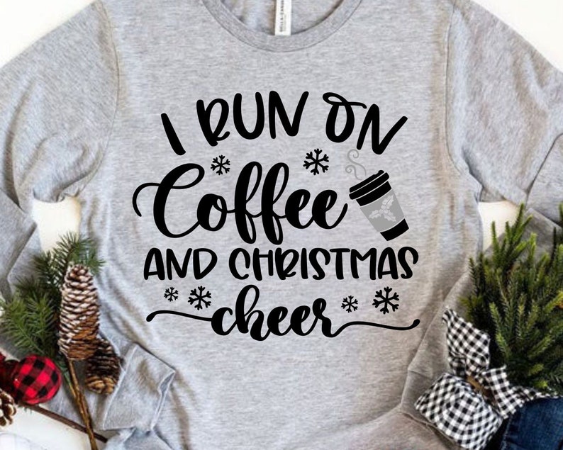 May include: Gray long-sleeve shirt with black text that reads "I run on coffee and christmas cheer" with a snowflake and a cup of coffee graphic.