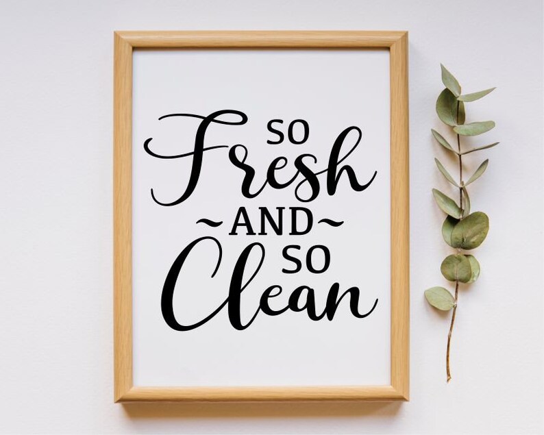 May include: A framed print with the text "So Fresh and So Clean" in a black cursive font on a white background. The frame is light brown wood.
