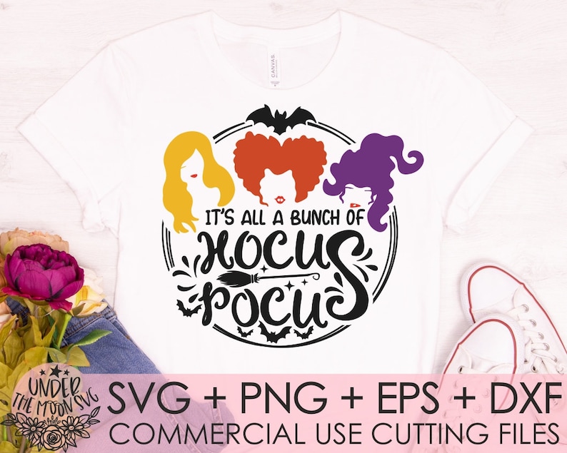 May include: A white t-shirt with a black and white graphic design featuring three witches with the text "It's all a bunch of Hocus Pocus".