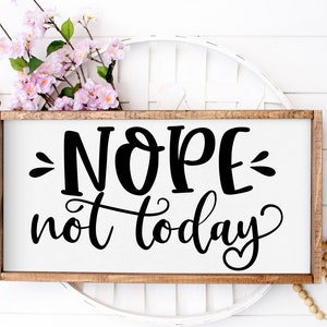 Puede incluir: Un letrero de madera con el texto "NOPE not today" en letras negras sobre fondo blanco. El letrero est&aacute; sobre una superficie de mimbre blanca.