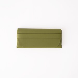 May include: Olive green clutch wallet with a wraparound strap closure. The wallet has a curved edge and a rectangular shape. The material appears to be leather or a leather-like material. The background is white.
