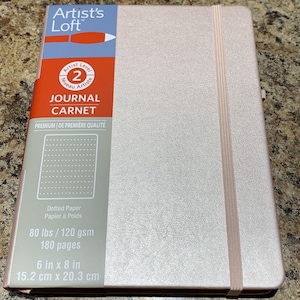 May include: A pink journal with a dotted paper interior. The journal is 6 inches by 8 inches and has 180 pages. The cover says "Artist's Loft" and "Journal Carnet".