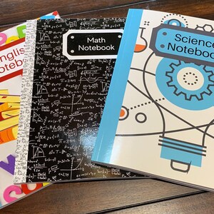 May include: Three notebooks with different subject matter: English, Math, and Science. Each notebook has a colorful cover with a design related to the subject. The English notebook has a red cover with a stack of colorful books and letters. The Math notebook has a black cover with white mathematical equations and symbols. The Science notebook has a white cover with a blue lightbulb and gears.
