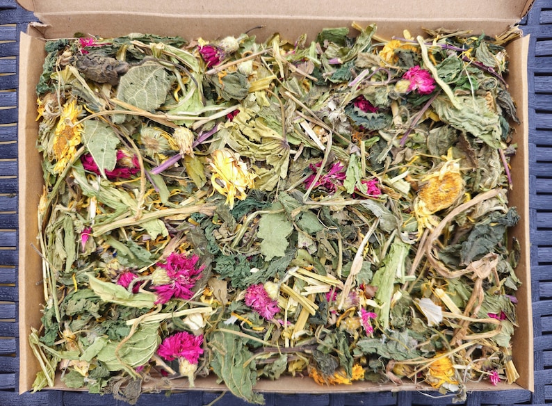 K&ouml;nnte beinhalten: Eine Kartonbox gef&uuml;llt mit einer Vielzahl getrockneter Kr&auml;uter und Blumen. Die Kr&auml;uter und Blumen sind eine Mischung aus Gr&uuml;n, Gelb und Rosa.