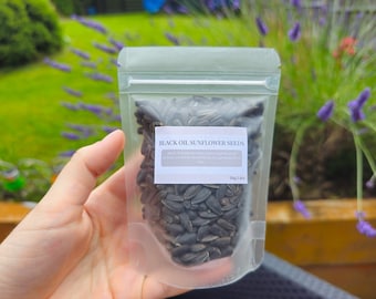 May include: A clear plastic bag filled with black oil sunflower seeds. The bag has a white label that reads "Black Oil Sunflower Seeds" and "500g/1.1lbs".