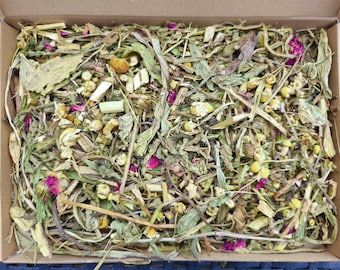 May include: A box filled with a variety of dried herbs and flowers, including green leaves, brown stems, yellow flowers, and pink petals.