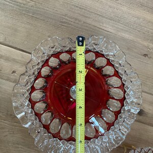 Puede incluir: Un juego de tres platos de pastel de vidrio vintage. El plato superior es rojo con un borde claro y festoneado. Los dos platos inferiores son transparentes con bordes festoneados. Los platos tienen un di&aacute;metro de 17,8 cm.
