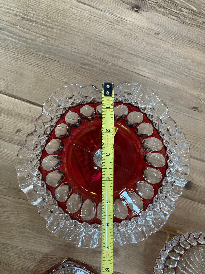 Puede incluir: Un juego de tres platos de pastel de vidrio vintage. El plato superior es rojo con un borde claro y festoneado. Los dos platos inferiores son transparentes con bordes festoneados. Los platos tienen un di&aacute;metro de 17,8 cm.
