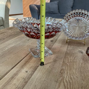 Puede incluir: Un juego de tres cuencos de vidrio transparente con un patr&oacute;n rojo en forma de diamante. Los cuencos est&aacute;n sobre una mesa de madera.