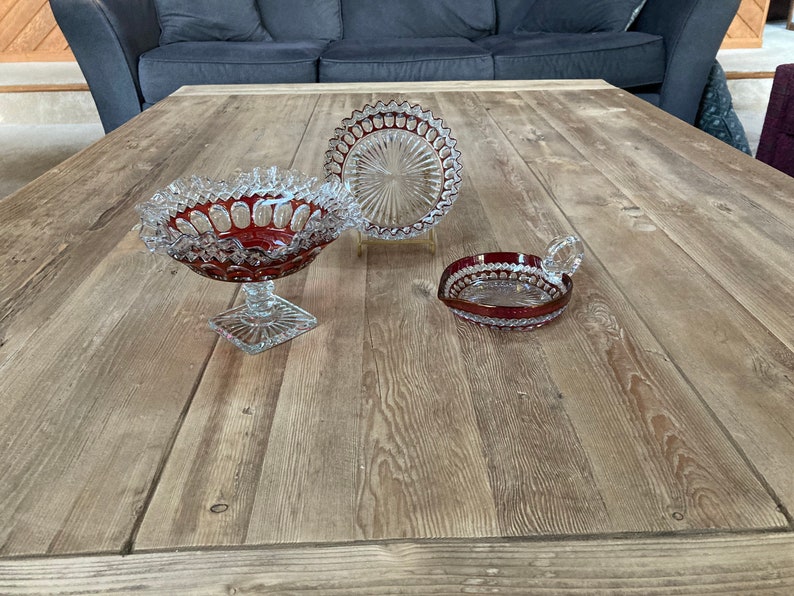 Puede incluir: Tres cuencos de vidrio con un dise&ntilde;o de vidrio cortado. Los cuencos est&aacute;n sobre una mesa de madera. Los cuencos son rojos y transparentes.