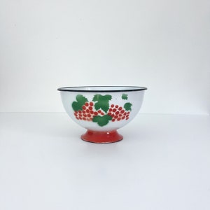 May include: White enamel bowl with a red and green grape design. The bowl has a black rim and a red base.