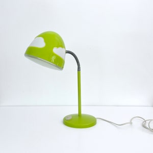 May include: A green desk lamp with a white cloud design on the shade. The lamp has a flexible neck and a round base.