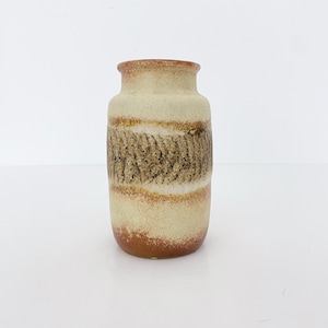 Puede incluir: Un jarrón pequeño de cerámica con un patrón de rayas marrones, blancas y beige. El jarrón tiene un cuerpo redondeado y una abertura ligeramente acampanada.