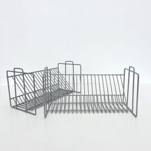 May include: Three gray metal wire storage baskets. Each basket has a rectangular shape with a grid-like design. The baskets are designed to hold items and have a minimalist aesthetic.