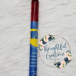 Pode incluir: Uma caneta personalizada com um design vermelho, azul e amarelo, com o texto "WD" e informa&ccedil;&otilde;es sobre o produto. A caneta tem uma ponta prateada e uma base preta. &Eacute; um instrumento de escrita &uacute;nico e feito &agrave; m&atilde;o.