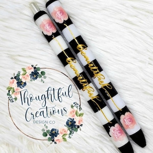 Pode incluir: Duas canetas com listras pretas e brancas e a palavra "Beautiful" em letras douradas. Cada caneta tem um desenho de rosa rosa e detalhes em preto e prata. As canetas s&atilde;o da Thoughtful Creations Design Co.