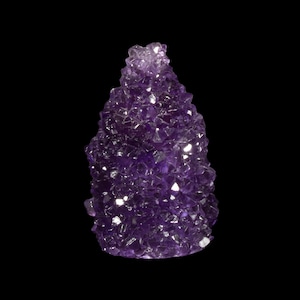 Pode incluir: Um grande aglomerado de cristais de ametista de cor roxa intensa. O cristal é composto por muitos cristais menores que estão agrupados. O cristal é liso e brilhante.