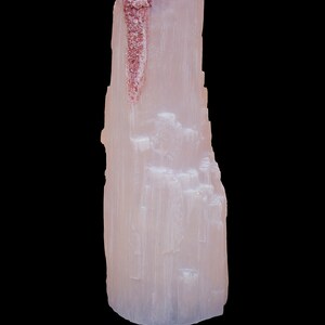 Pode incluir: Um grande cristal de selenita branco com uma faixa marrom avermelhada no lado. O cristal é liso e tem uma textura em camadas.