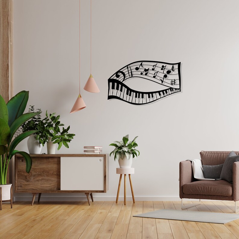 May include: Black metal wall art depicting a musical staff with notes and a piano keyboard. The art is mounted on a white wall above a wooden cabinet with a white door. There are two pink pendant lights hanging from the ceiling.