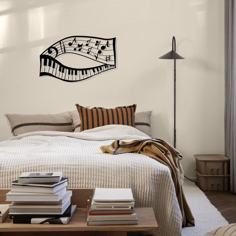 May include: Black metal wall art depicting a musical staff with notes and a piano keyboard. The art is mounted on a white wall above a bed with a white comforter and brown throw blanket.