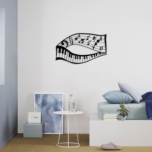 May include: Black metal wall art featuring a musical note design with a piano keyboard. The art is displayed on a white wall above a white table and a light blue bed with pillows.