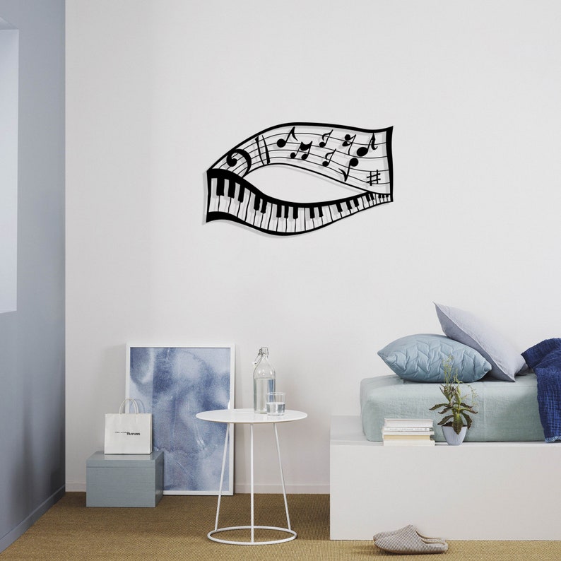 May include: Black metal wall art featuring a musical note design with a piano keyboard. The art is displayed on a white wall above a white table and a light blue bed with pillows.