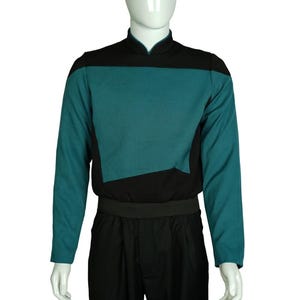 May include: A teal and black long-sleeved shirt with a high collar. The shirt has a black panel across the chest and a black belt.