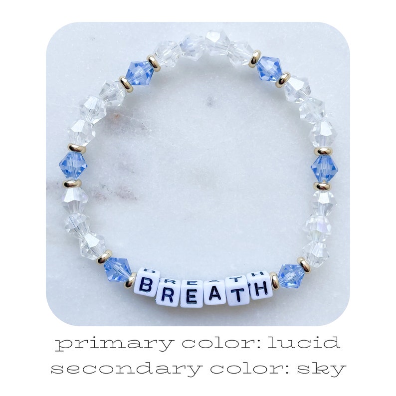 Pu&ograve; includere: Un braccialetto di perline trasparenti e blu, con la parola "BREATH" scritta con perline di lettere bianche. Il braccialetto presenta perline di cristallo trasparenti e blu, separate da distanziatori color oro.