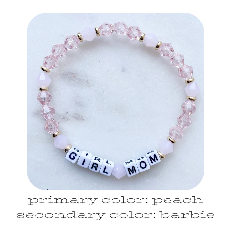 Pu&ograve; includere: Un braccialetto di perline rosa con le parole "GIRL MOM" scritte con perline di lettere bianche. Il braccialetto presenta perline color pesca e dettagli dorati. Il braccialetto &egrave; un gioiello delicato.