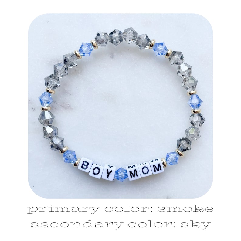 Pu&ograve; includere: Un braccialetto di perline con le parole "BOY MOM" scritte con perline di lettere bianche. Il braccialetto presenta perline di cristallo grigie e azzurre, intervallate da distanziatori color oro. Il colore primario &egrave; fumo e il colore secondario &egrave; cielo.