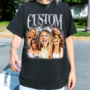 May include: Black t-shirt with the word "CUSTOM" in silver glitter lettering. The shirt features a collage of five women with various expressions. The women are surrounded by a smoky, ethereal effect.