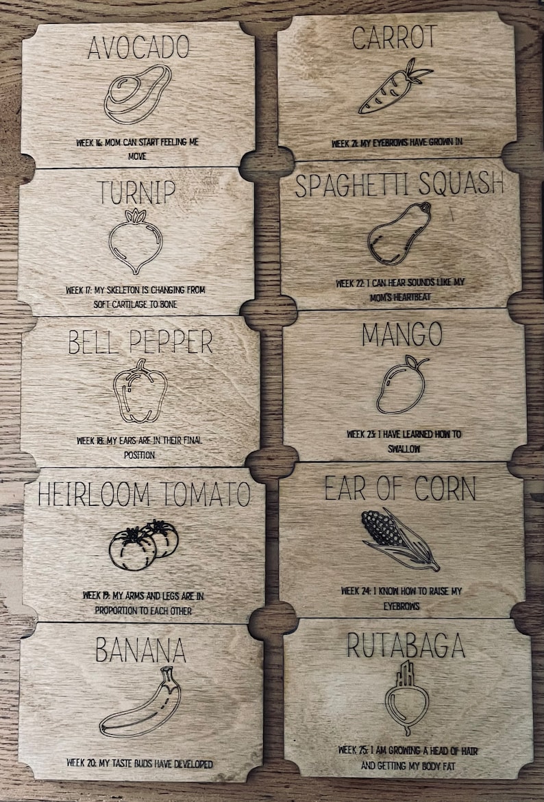 May include: A set of 10 wooden cards with illustrations of different fruits and vegetables. Each card has a title and a description of the stage of development of a baby during pregnancy. For example, the avocado card says "Week 16: Mum can start feeling me move".