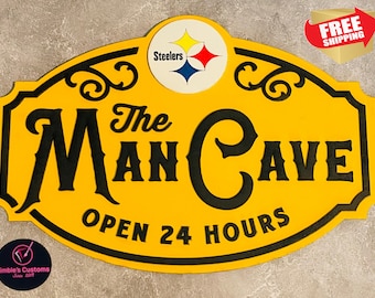 May include: Yellow and black wooden sign with the text "The Man Cave Open 24 Hours". The sign has a Steelers logo in the top center.