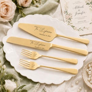 May include: A gold-toned cake serving set consisting of a serrated cake server, a knife, and two forks. The server and knife are engraved with the text The Lykasons and December 10, 2026, while the two forks feature the engraved letter L.