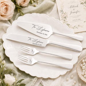 May include: A silver-toned cake serving set consisting of a serrated cake server and a knife, both engraved with "The Lykasons" and "December 10, 2026," alongside two matching forks each featuring a cursive "L" monogram on the handle.