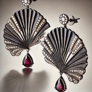 Może przedstawiać: Para czarnych i srebrnych kolczyków z wzorem w kształcie wachlarza i rubinowym kamieniem szlachetnym w kształcie łzy. Kolczyki są ozdobione małymi diamentami.