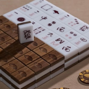 May include: A set of Mahjong tiles, featuring a mix of white and wooden tiles. The wooden tiles have a fan design. The white tiles display various symbols and characters in red. Several game chips with a fan design are also visible.
