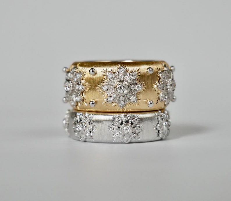 Puede incluir: Dos anillos apilados, uno dorado y otro plateado, cada uno adornado con intrincados dise&ntilde;os de diamantes en forma de copo de nieve. El anillo dorado tiene un acabado texturizado y peque&ntilde;os detalles redondos. El anillo plateado tiene un acabado liso.