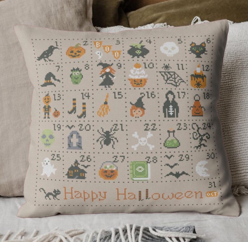 K&ouml;nnte beinhalten: Ein beiges Kissen mit einem Kreuzstich-Design mit 31 Halloween-Motiven, die von 1 bis 31 nummeriert sind. Die Motive umfassen einen Geist, eine Hexe, eine Spinne, einen K&uuml;rbis, einen Sch&auml;del, einen Kessel und eine Fledermaus. Das Kissen hat auch den Text "Happy Halloween" und "31 OCT" aufgedruckt.
