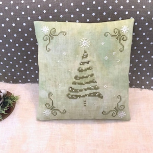 May include: A green and white embroidered pillow with a stylized Christmas tree design. The pillow is made of a light green linen fabric and has a white background.
