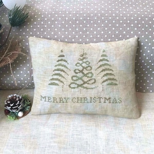 May include: A beige pillow with a green embroidered design of three stylized Christmas trees and the text "Merry Christmas".