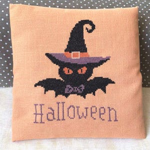 Schema punto croce di Halloween in PDF con gattino nero in costume da pipistrello e cappello da strega, motivo per ricamo fai da te spettrale.