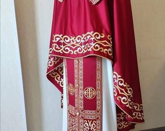 May include: A red and white liturgical vestment with gold embroidery. The vestment has a long, flowing robe with a decorative collar and a matching stole. The embroidery features intricate patterns and designs.