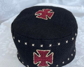 Puede incluir: Sombrero tejido negro con dos cruces bordadas rojas. Las cruces tienen contornos blancos.