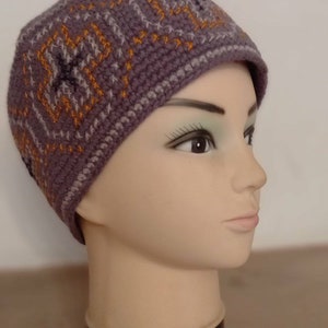 May include: A gray and orange crocheted beanie with a geometric pattern. The beanie is on a mannequin head.