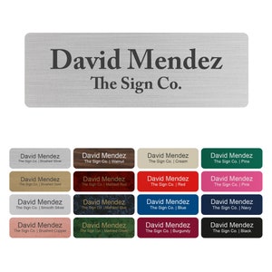 May include: A rectangular nameplate with the text "David Mendez" and "The Sign Co." in a dark font. Below are color swatches with the same text, including brushed silver, walnut, cream, pine, brushed gold, marbled red, red, pink, smooth silver, marbled blue, blue, navy, brushed copper, marbled green, burgundy, and black.