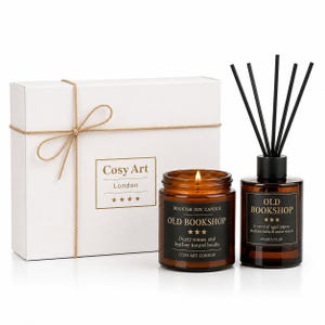 Op de afbeelding: Een witte geschenkdoos met touw, een brandende sojakaars in een amberkleurige glazen pot met het label Old Bookshop, en een geurstokjesdiffuser in een amberkleurige glazen fles met zwarte stokjes. Labels zijn voorzien van gouden tekst.